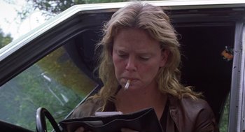 Movie still from “Monster” (2003), directed by Patty Jenkins – A woman smoking a cigarette while sitting in the back of a car; Close Up shot, Over the shoulder angle