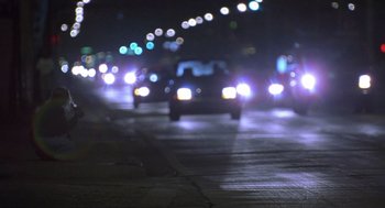 Movie still from “Monster” (2003), directed by Patty Jenkins – A blurry image of a car driving down a street at night; Wide shot, Over the shoulder angle