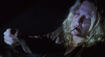 Movie still from “Monster” (2003), directed by Patty Jenkins – A woman smoking a cigarette while sitting in a dark room; Close Up shot, Low angle