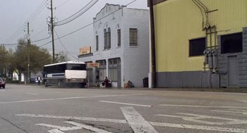 Movie still from “Monster” (2003), directed by Patty Jenkins – A bus driving down a street next to a building; Extreme Wide shot, Low angle