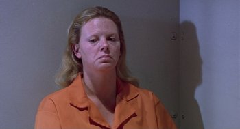 Movie still from “Monster” (2003), directed by Patty Jenkins – A woman in an orange shirt is in a room; Close Up shot, Low angle