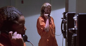 Movie still from “Monster” (2003), directed by Patty Jenkins – A woman talking on a phone in an orange jumpsuit; Medium shot, High angle