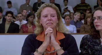 Movie still from “Monster” (2003), directed by Patty Jenkins – A woman with her hands clasped in front of a crowd; Medium shot, High angle