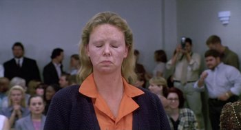Movie still from “Monster” (2003), directed by Patty Jenkins – A woman with her eyes closed in front of a group of people; Close Up shot, Low angle