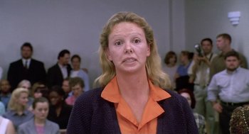 Movie still from “Monster” (2003), directed by Patty Jenkins – A woman in an orange and black shirt is in front of an audience; Close Up shot, Low angle