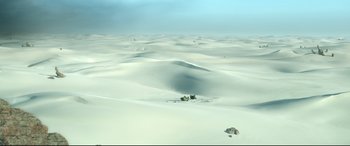 Movie still from “Monster Hunter” (2020), directed by Paul W.S. Anderson – A view of a desert landscape with sand dunes and rocks; Extreme Wide shot, High angle