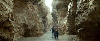 Movie still from “Monster Hunter” (2020), directed by Paul W.S. Anderson – Two people are walking through a narrow canyon; Wide shot, High angle