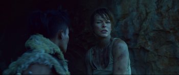 Movie still from “Monster Hunter” (2020), directed by Paul W.S. Anderson – A woman and a young man are in a dark cave; Close Up shot, Over the shoulder angle