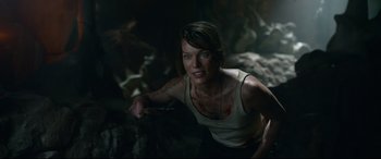 Movie still from “Monster Hunter” (2020), directed by Paul W.S. Anderson – A woman in a white tank top is holding a knife; Medium shot, Over the shoulder angle