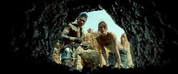 Movie still from “Monster Hunter” (2020), directed by Paul W.S. Anderson – A man and a woman standing next to each other in front of rocks; Medium shot, Low angle