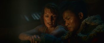 Movie still from “Monster Hunter” (2020), directed by Paul W.S. Anderson – A woman sitting next to a man in a dark room; Close Up shot, Over the shoulder angle