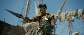 Movie still from “Monster Hunter” (2020), directed by Paul W.S. Anderson – A man in a costume standing next to a bunch of boats; Medium shot, Low angle