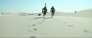 Movie still from “Monster Hunter” (2020), directed by Paul W.S. Anderson – Two men are running through the sand dunes; Extreme Wide shot, High angle