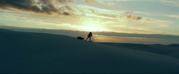 Movie still from “Monster Hunter” (2020), directed by Paul W.S. Anderson – A man riding a snowboard down the side of a snow covered slope; Extreme Wide shot, Low angle