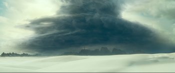 Movie still from “Monster Hunter” (2020), directed by Paul W.S. Anderson – Dark storm clouds are rolling in over a snow covered field; Extreme Wide shot, High angle