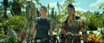 Movie still from “Monster Hunter” (2020), directed by Paul W.S. Anderson – A woman and a man are standing in the woods; Medium shot, Low angle