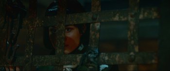 Movie still from “Monster Hunter” (2020), directed by Paul W.S. Anderson – A woman looking through a metal gate; Close Up shot, Over the shoulder angle