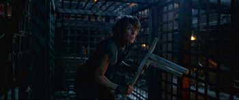 Movie still from “Monster Hunter” (2020), directed by Paul W.S. Anderson – A woman holding a wooden board in a dark room; Medium shot, Low angle