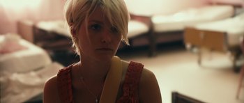 Movie still from “Monsters” (2010), directed by Gareth Edwards – A woman with short blonde hair wearing a pink dress; Close Up shot, Over the shoulder angle