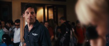 Movie still from “Monsters” (2010), directed by Gareth Edwards – A crowd of people standing in a room; Close Up shot, Over the shoulder angle