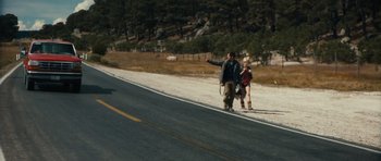 Movie still from “Monsters” (2010), directed by Gareth Edwards – A man and a boy riding skateboards down the side of a road; Wide shot, High angle