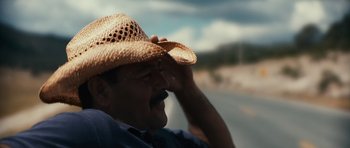 Movie still from “Monsters” (2010), directed by Gareth Edwards – A man wearing a cowboy hat while standing next to a road; Close Up shot, Low angle