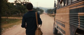 Movie still from “Monsters” (2010), directed by Gareth Edwards – A man walking down a dirt road next to a bus; Wide shot, Over the shoulder angle