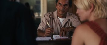 Movie still from “Monsters” (2010), directed by Gareth Edwards – An older man writing on a piece of paper; Close Up shot, Over the shoulder angle