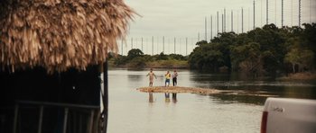 Movie still from “Monsters” (2010), directed by Gareth Edwards – A group of people standing on top of a rock in the water; Extreme Wide shot, Low angle