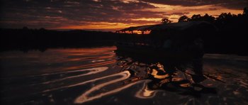 Movie still from “Monsters” (2010), directed by Gareth Edwards – A boat in a body of water at sunset; Extreme Wide shot, Low angle