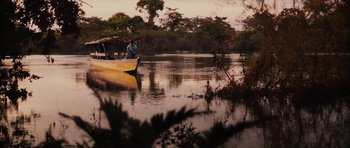 Movie still from “Monsters” (2010), directed by Gareth Edwards – A boat is traveling down a river near a forest; Extreme Wide shot, Low angle