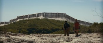 Movie still from “Monsters” (2010), directed by Gareth Edwards – A man standing on top of a sandy hill; Extreme Wide shot, Low angle