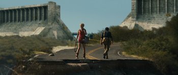 Movie still from “Monsters” (2010), directed by Gareth Edwards – Two people walking down a road near a mountain; Wide shot, Low angle