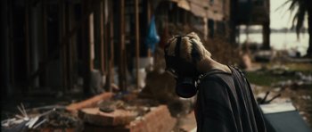 Movie still from “Monsters” (2010), directed by Gareth Edwards – A person wearing a gas mask in front of a building; Close Up shot, Over the shoulder angle