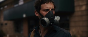 Movie still from “Monsters” (2010), directed by Gareth Edwards – A man wearing a gas mask while standing outside; Close Up shot, Low angle
