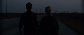 Movie still from “Monsters” (2010), directed by Gareth Edwards – Two people walking down a road holding hands; Medium shot, Low angle