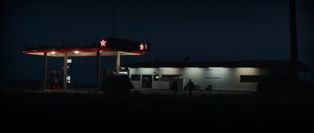 Movie still from “Monsters” (2010), directed by Gareth Edwards – A gas station at night with a car parked in front of it; Extreme Wide shot, Low angle