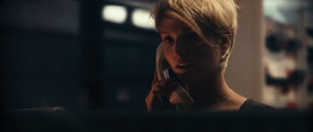 Movie still from “Monsters” (2010), directed by Gareth Edwards – A woman talking on a phone while sitting at a desk; Close Up shot, Low angle