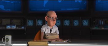 Movie still from “Monsters vs. Aliens” (2009), directed by Conrad Vernon – An animated bald man sitting at a desk with papers; Medium shot, Over the shoulder angle
