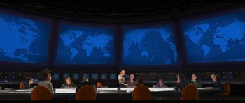Movie still from “Monsters vs. Aliens” (2009), directed by Conrad Vernon – A group of people sitting around a table with a map on the wall behind them; Extreme Wide shot, Low angle