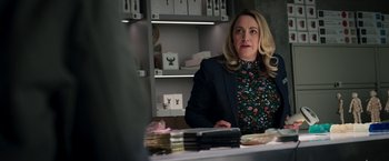 Movie still from “Moon Knight” (2022), directed by Mohamed Diab – A woman sitting at a table in front of stacks of books; Medium shot, Over the shoulder angle