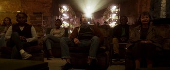 Movie still from “Moon Knight” (2022), directed by Mohamed Diab – A man sitting on a chair in front of a light; Wide shot, Low angle