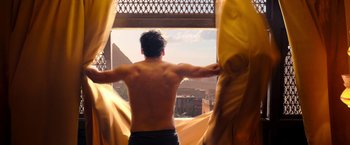 Movie still from “Moon Knight” (2022), directed by Mohamed Diab – A man standing in front of a window looking out at a city; Medium shot, Low angle