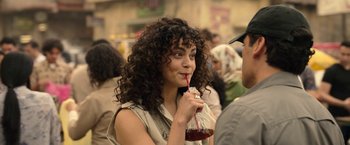 Movie still from “Moon Knight” (2022), directed by Mohamed Diab – A woman with curly brown hair holding a drink; Close Up shot, Over the shoulder angle