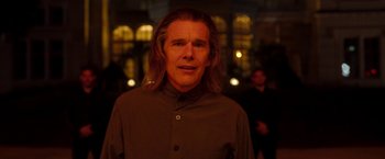 Movie still from “Moon Knight” (2022), directed by Mohamed Diab – A man with long blonde hair standing in front of a building; Close Up shot, Over the shoulder angle