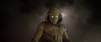 Movie still from “Moon Knight” (2022), directed by Mohamed Diab – A person wearing a hooded costume with glowing eyes; Medium shot, Low angle