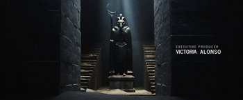Movie still from “Moon Knight” (2022), directed by Mohamed Diab – A statue of a man with a sword and a helmet on his head stands in the middle of the stairs; Wide shot, Low angle
