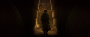Movie still from “Moon Knight” (2022), directed by Mohamed Diab – A man is standing in the dark in front of a stone wall; Wide shot, Low angle