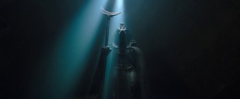 Movie still from “Moon Knight” (2022), directed by Mohamed Diab – A statue of a person holding a staff in a dark room; Wide shot, Low angle