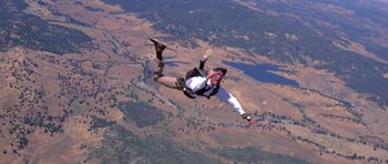 Movie still from “Moonraker” (1979), directed by Lewis Gilbert – A skydiver is in the air with his arms outstreched; Wide shot, Low angle